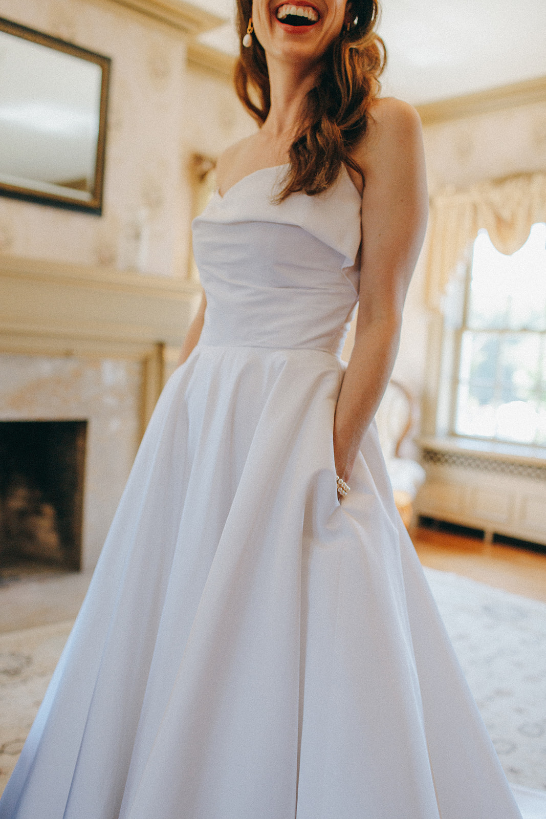 A bride laughs in her Sarah Seven gown in the bridal suite of the Felt Mansion