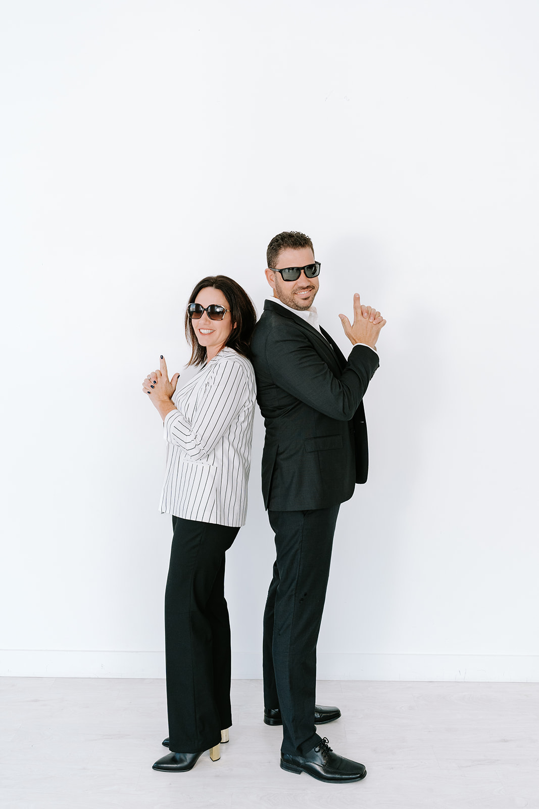 two realtors posing like Charlie's Angels with sunglasses on