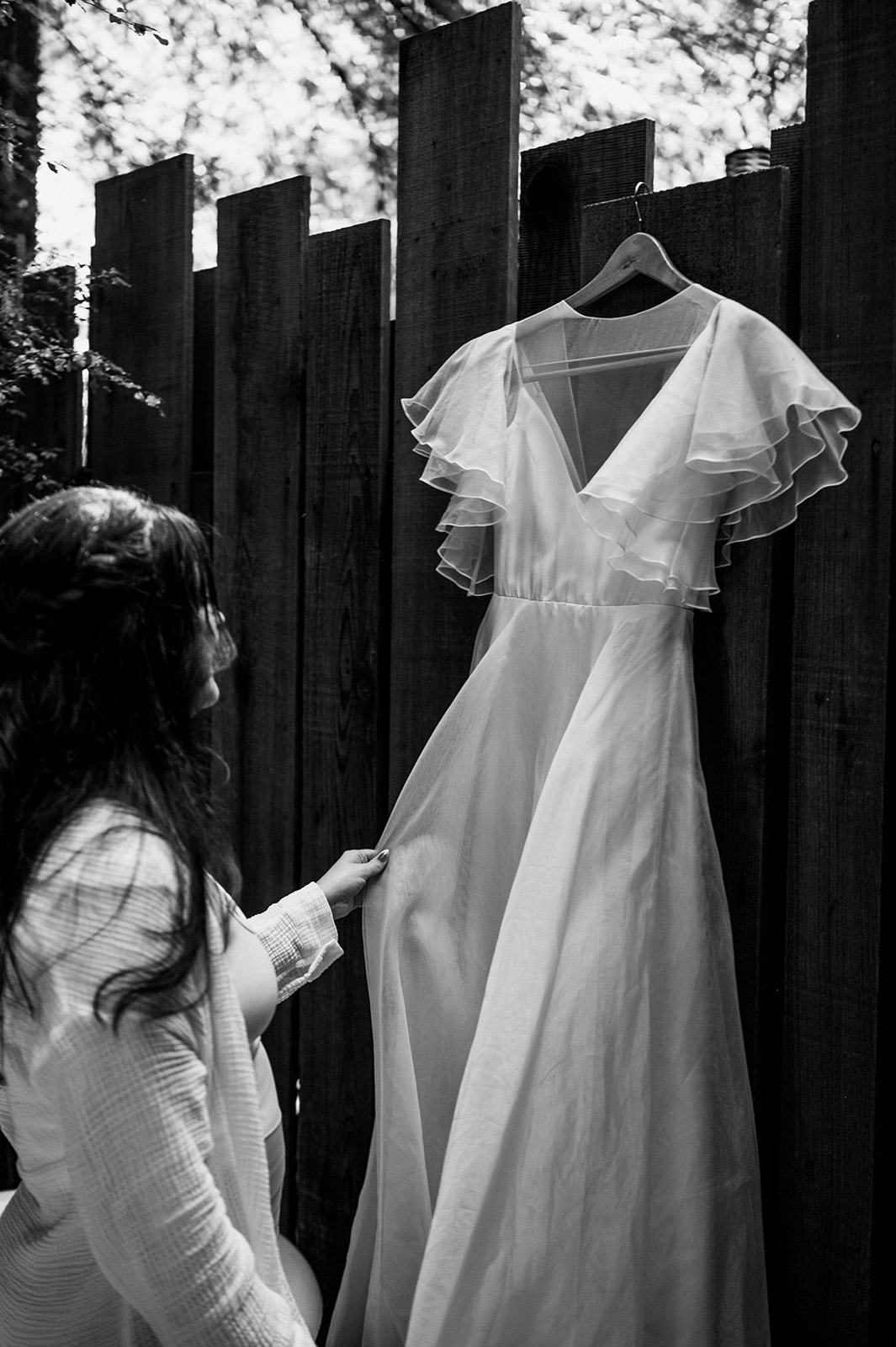 Black and white photo of bride looking at her wedding dress.
