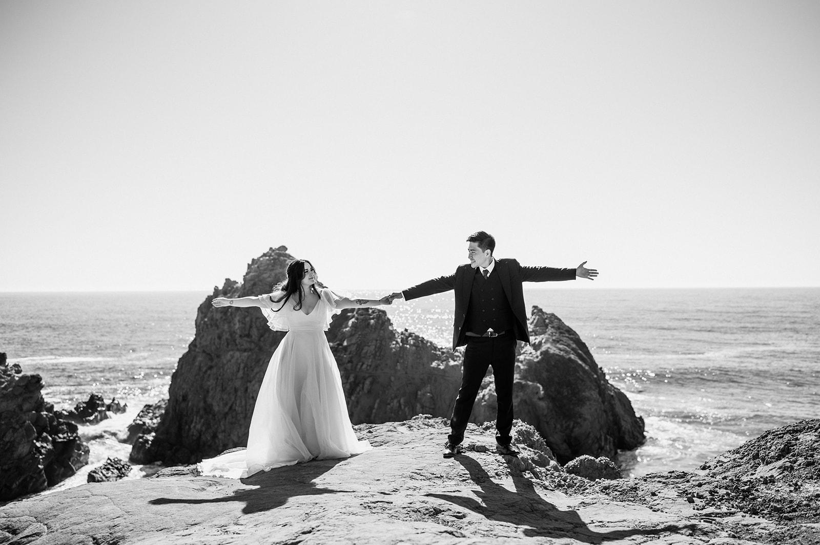 Bride and groom dancing on cliffs in Big Sur