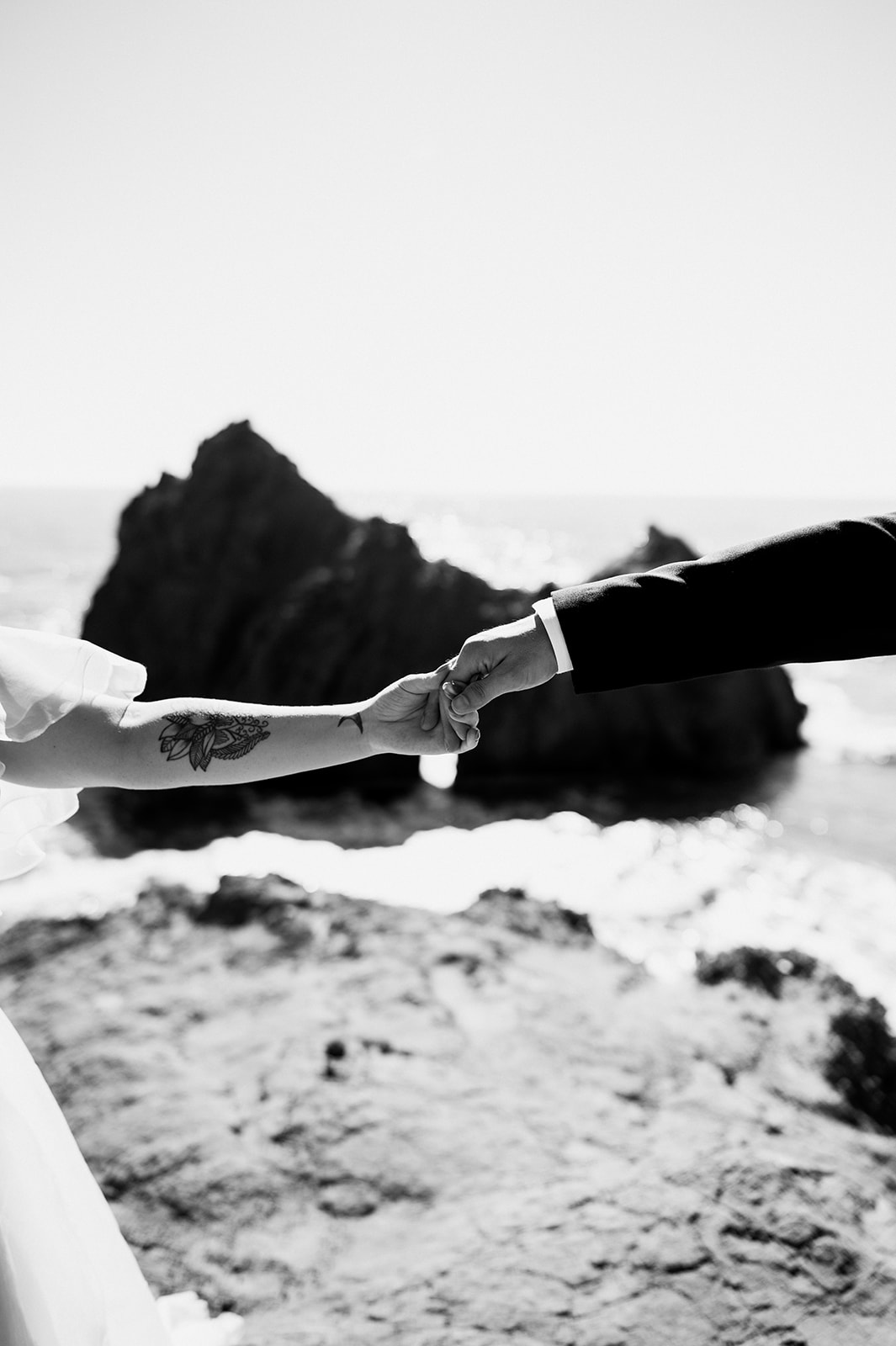 Coast of California, a newly married couple holding hands in the sunset.