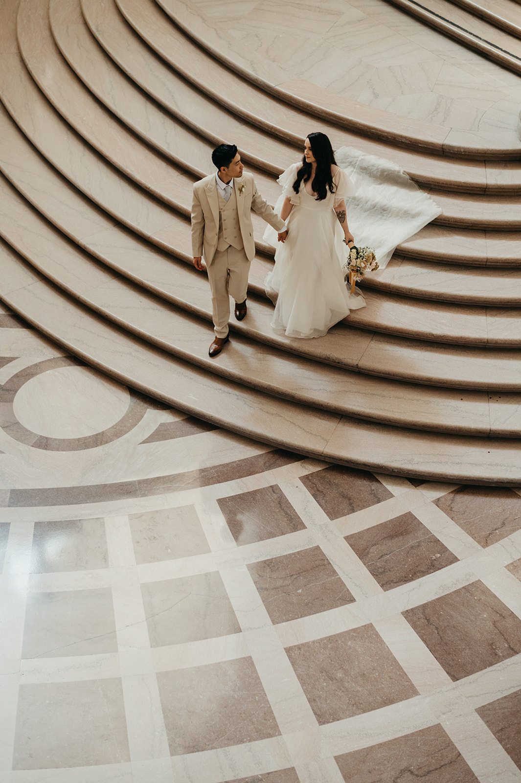 Bride and groom on beautiful massive stair case at San Francisco City Hall.