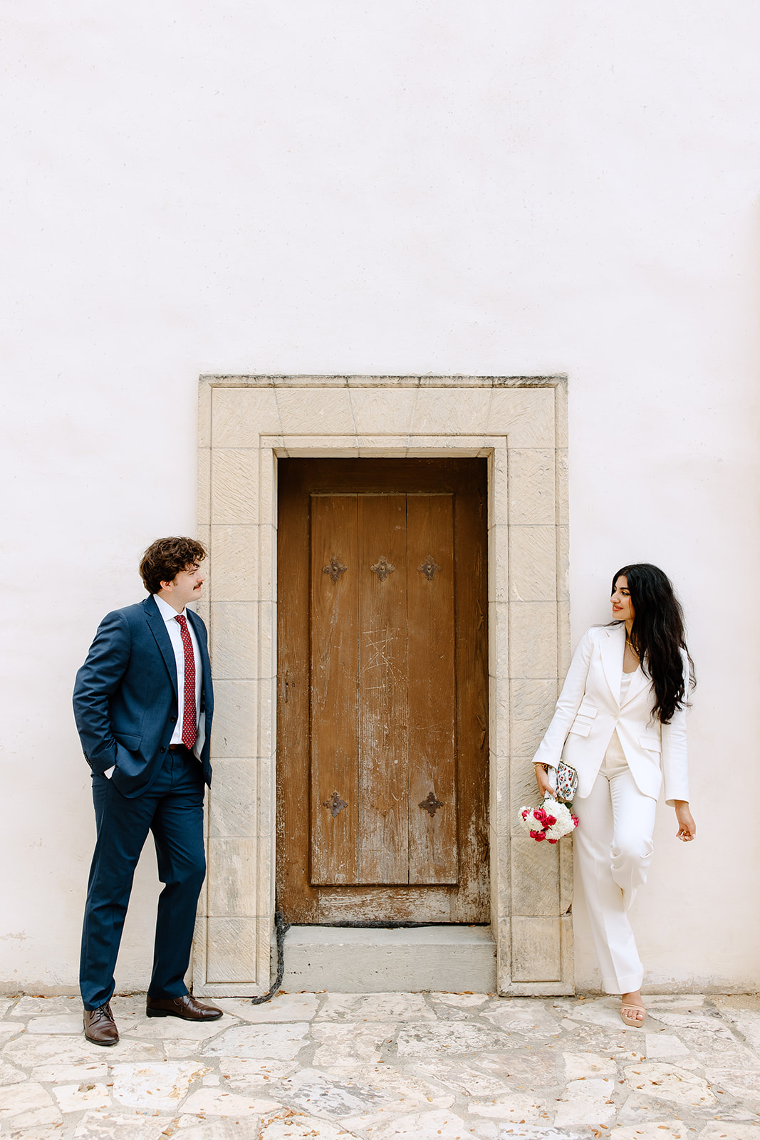 Bride and groom leaning against a door