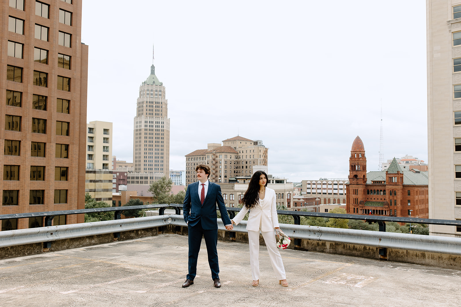 Bride and groom hold hands in front of San Antonio skyline