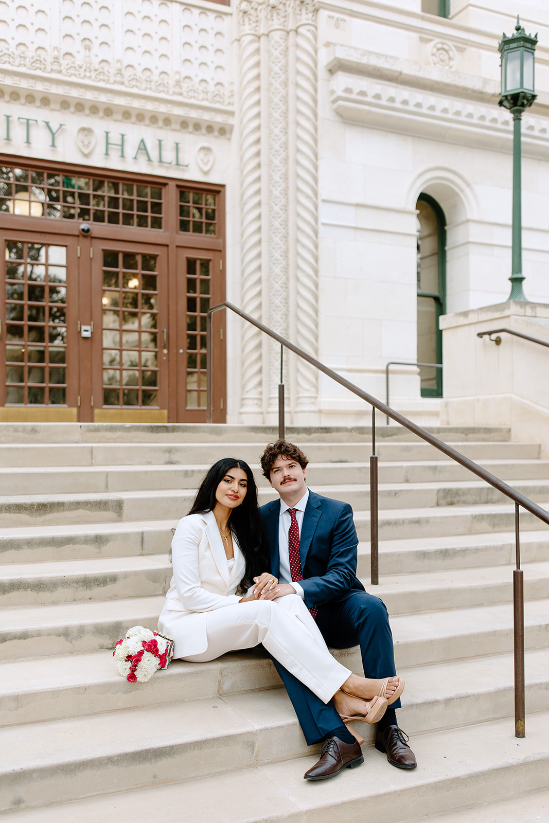 Bride and groom sitting on city hall steps