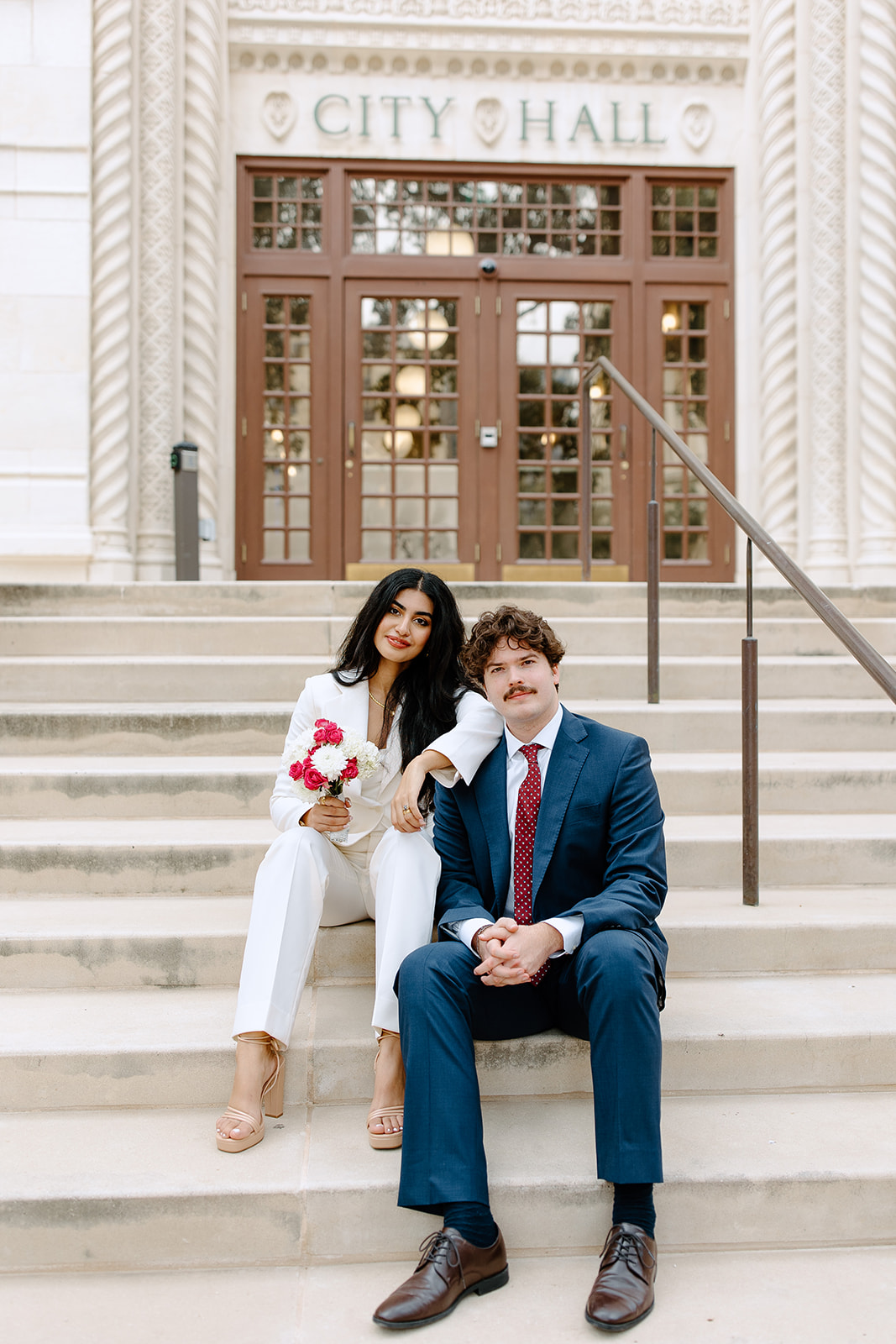 Bride and groom sitting on city hall steps