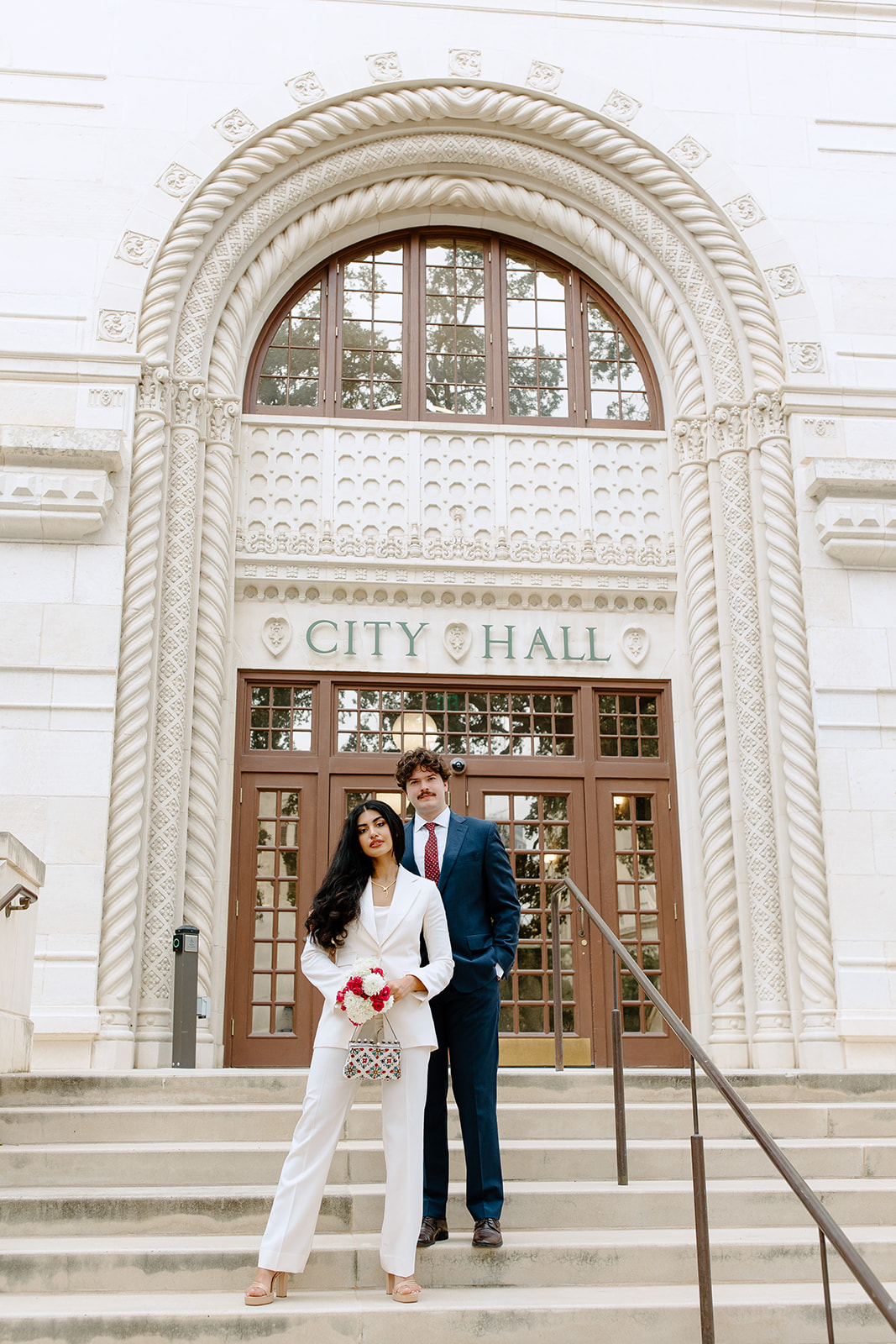 Bride and groom standing on city hall steps