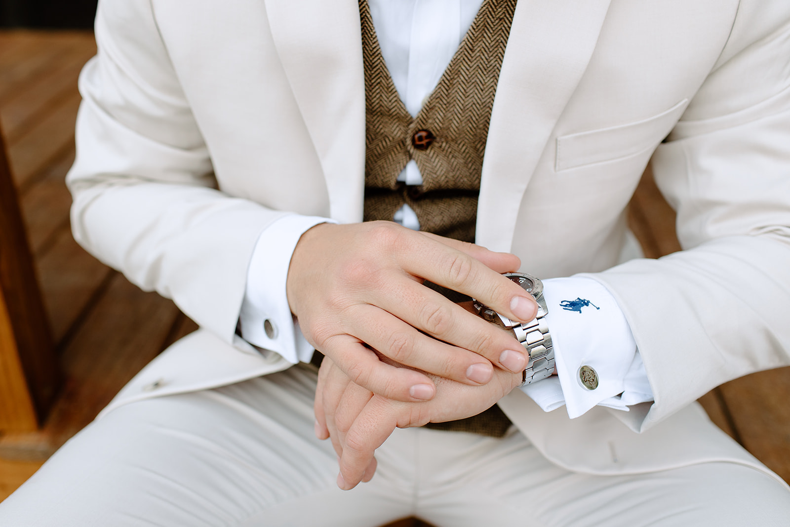 Groom adjusting his cuff links and watch