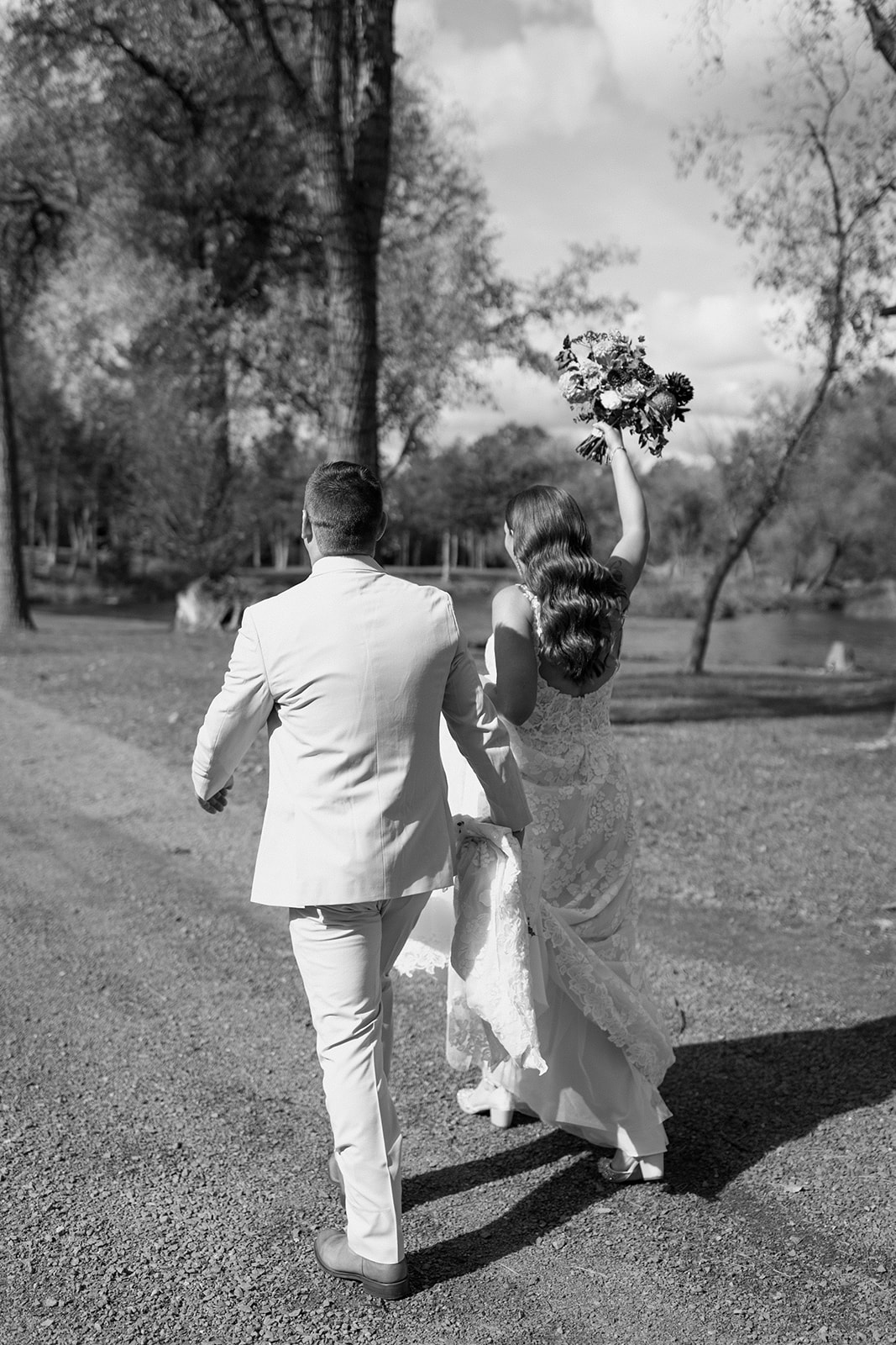 Bride and groom cheer as they walk towards their wedding party