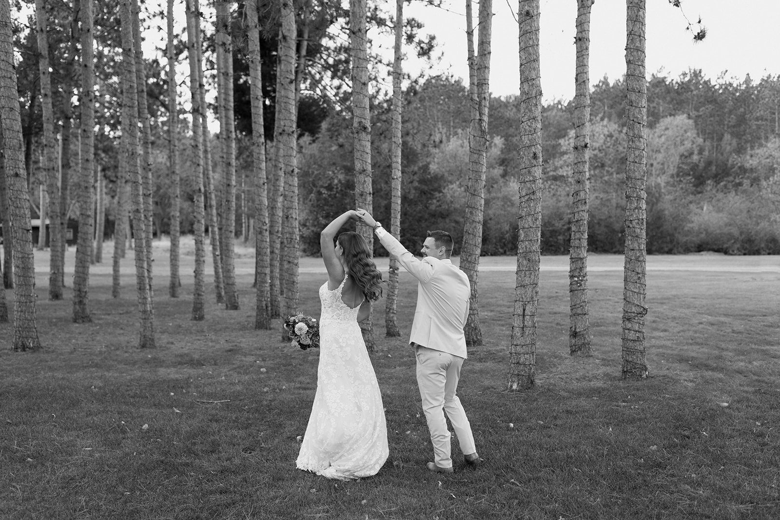 Groom twirls bride in between pine trees