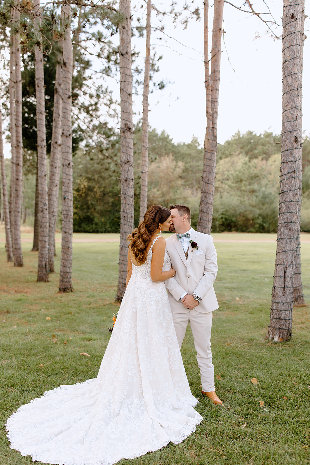 Bride and groom share a kiss between pine trees