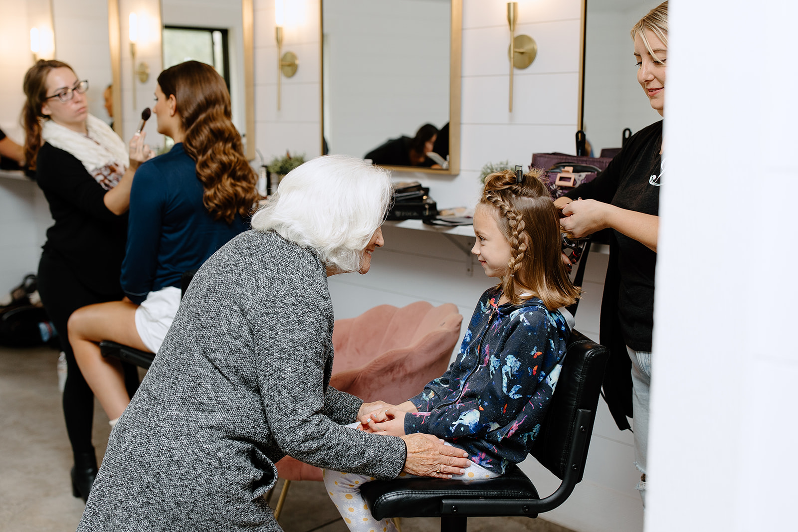 Woman smiling at the flower girl getting her hair done