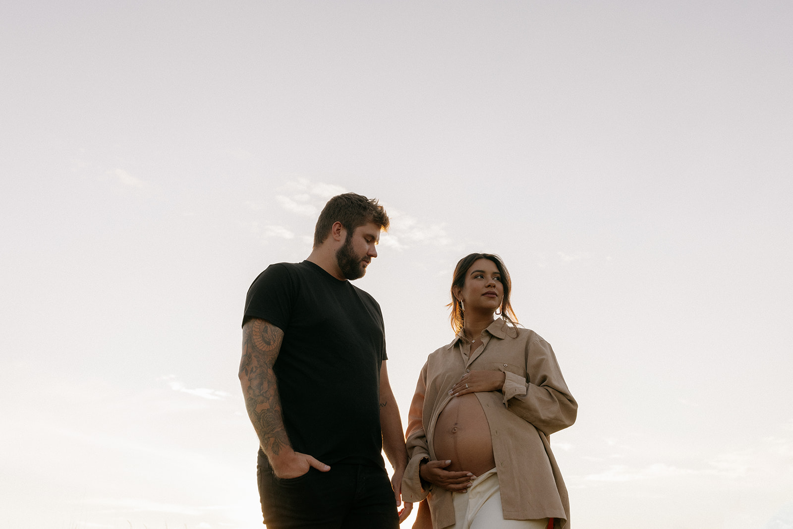 Mom and dad hang out in field during their maternity session