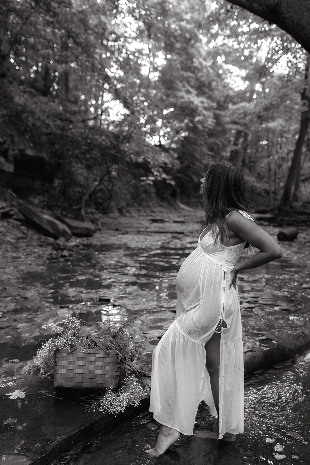 Mom wears a white dress during maternity session in water