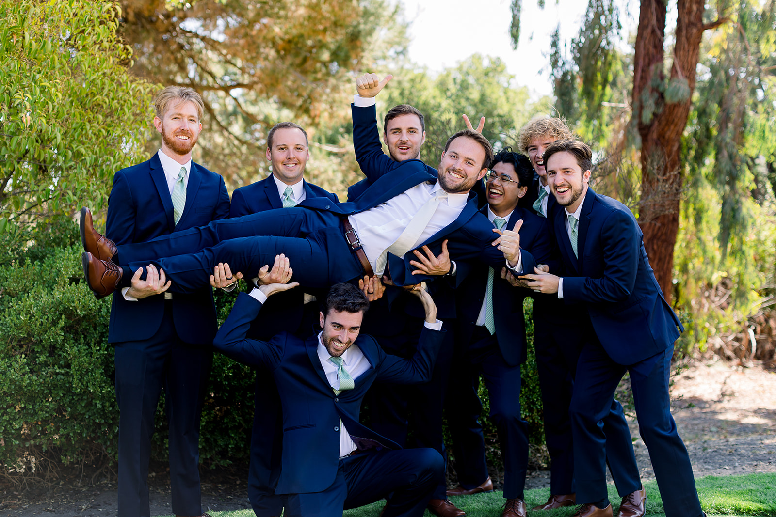 Groomsmen raising the groom in a cheerful toast, capturing the camaraderie before the ceremony
