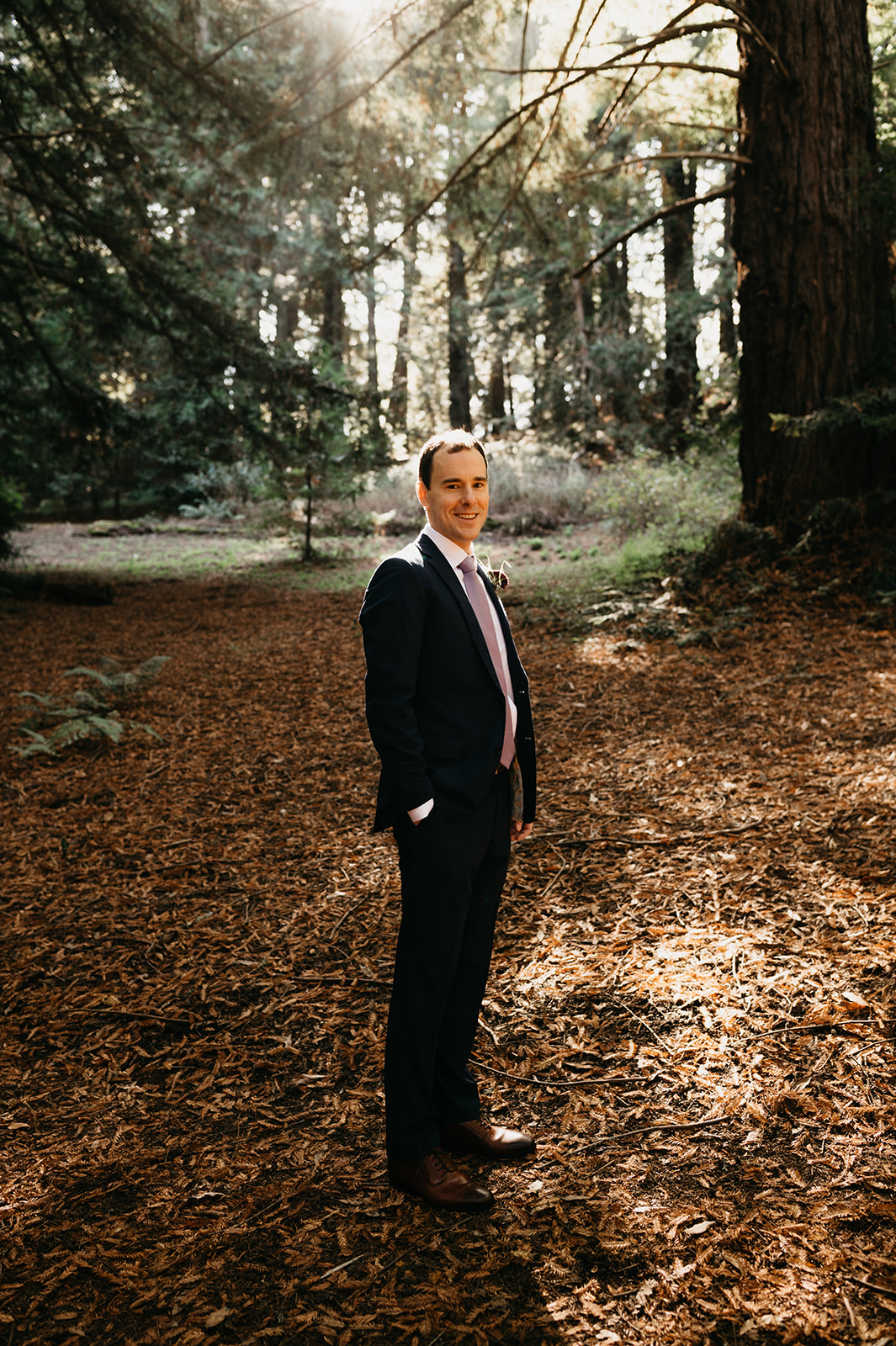 The groom waits for the bride at the ceremony spot in the forest in Big Sur, California.