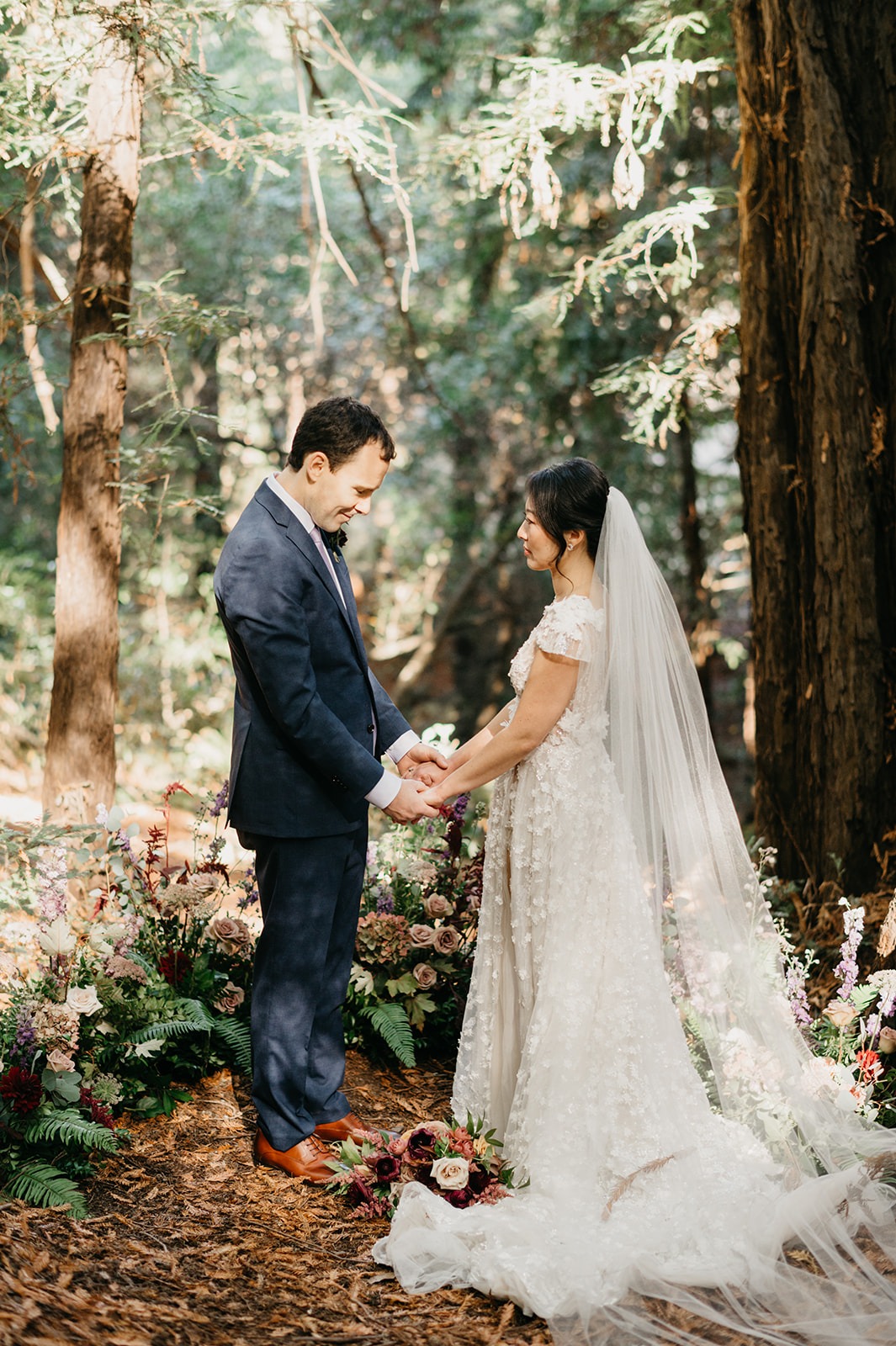 Bride and groom during their intimate ceremony in the forest surrounded by tall redwood trees in Post Ranch 