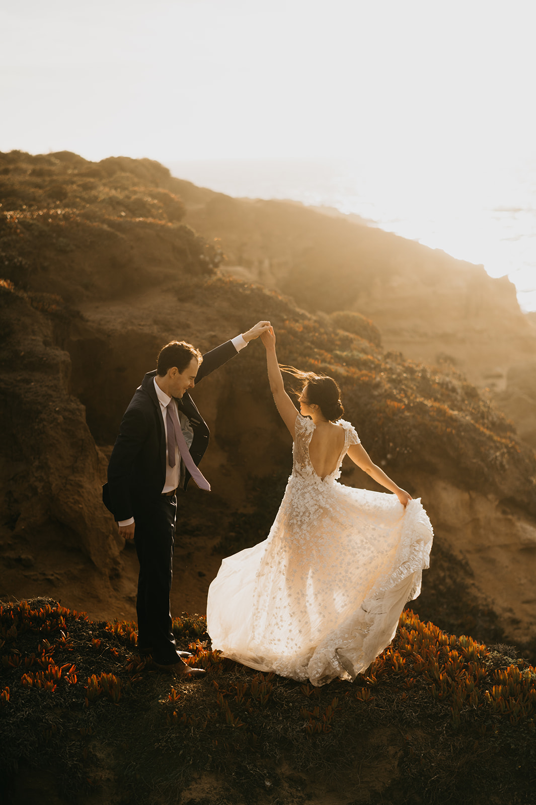 Bride and groom dancing in the sunset on a cliff in Big Sur California.