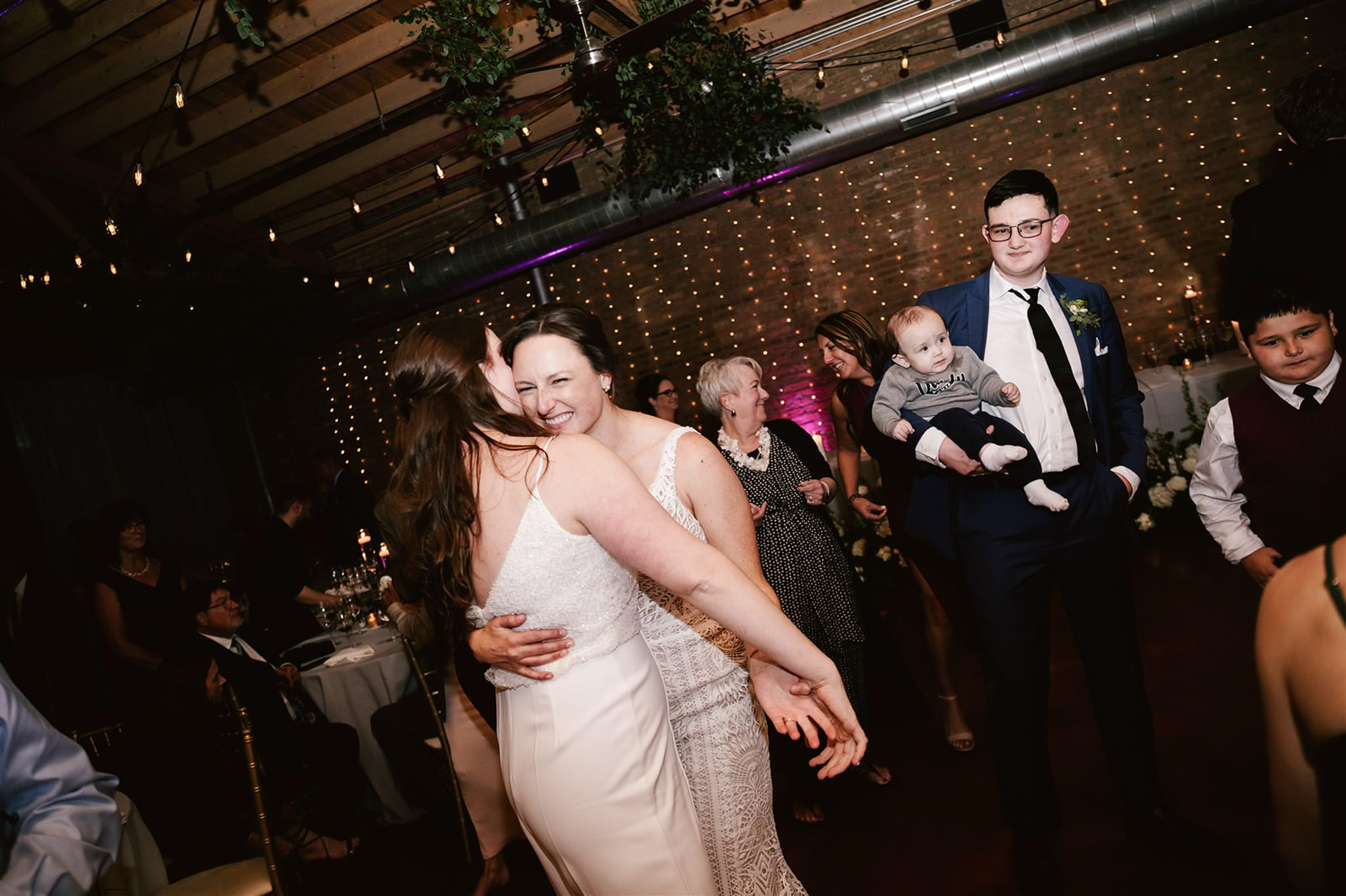 Guests joining the two brides on the dance floor, creating a lively and joyous atmosphere at Loft on Lake.