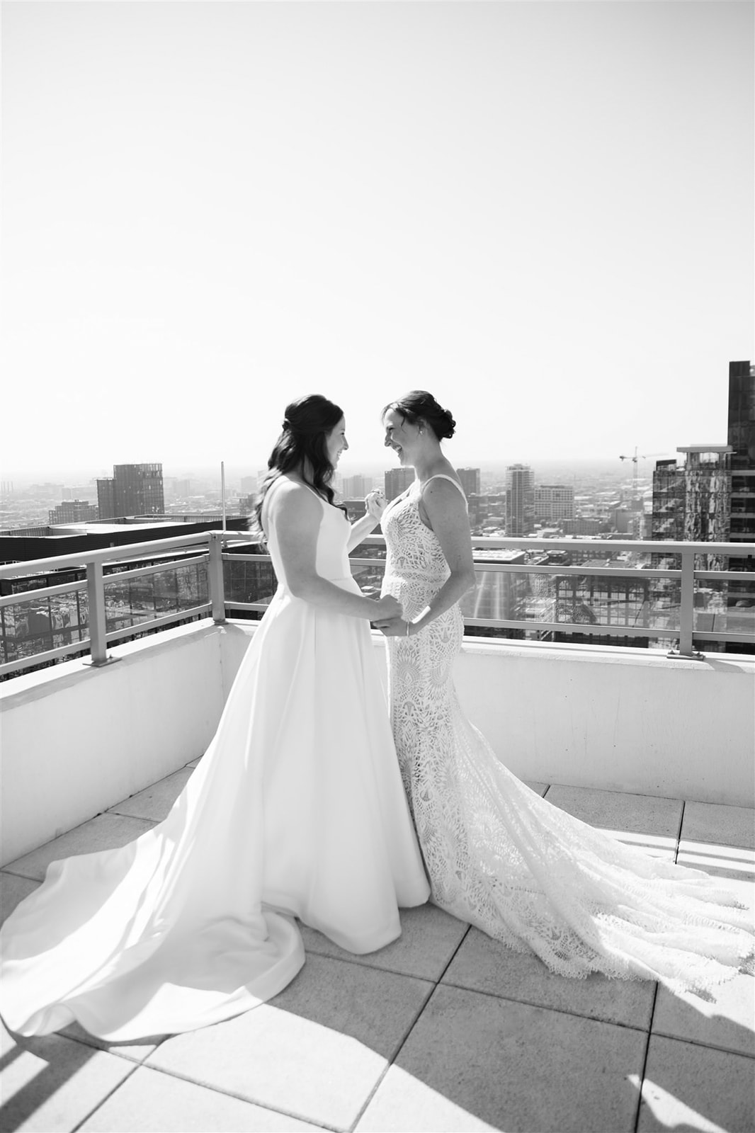 Two brides sharing a first look on Chicago rooftop and skyline backdrop, embracing in a moment of love and anticipation.