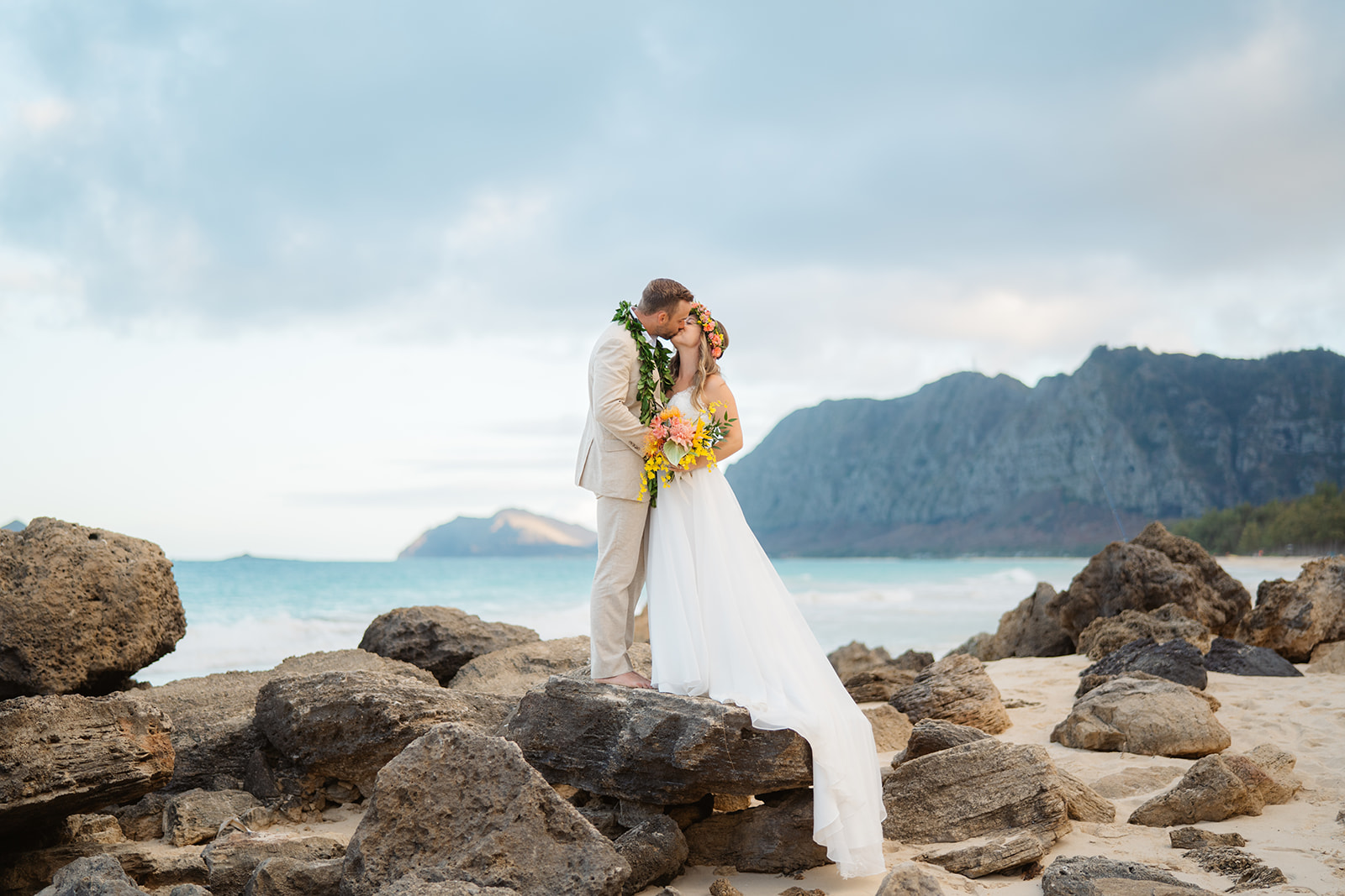 A bride and groom embrace on the beach during their oahu elopement by photographer Colby Moore.