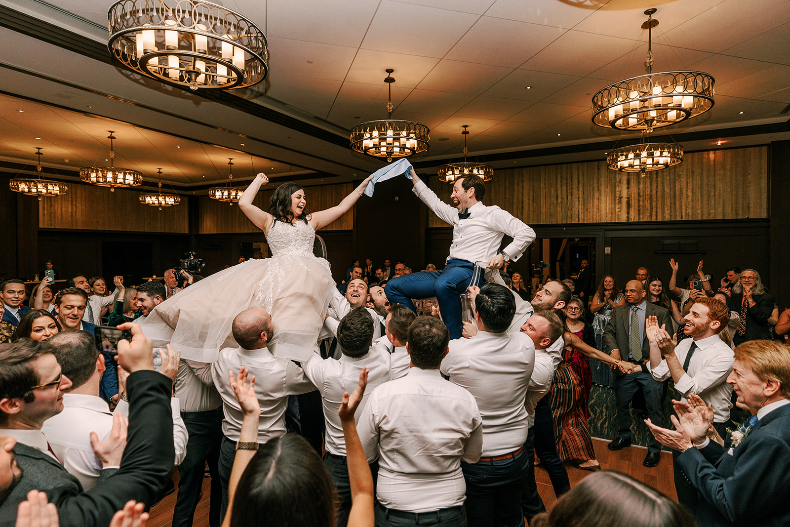 bride and groom hold a napkin and dance to the hora on their wedding day at the edgewater hotel in madison, wi