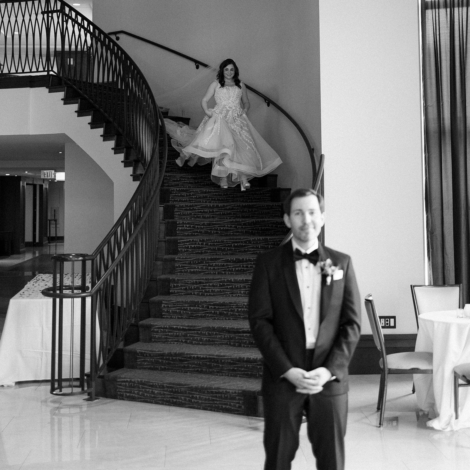bride walks down spiral staircase at the edgewater hotel to see her groom for the first time on her wedding day