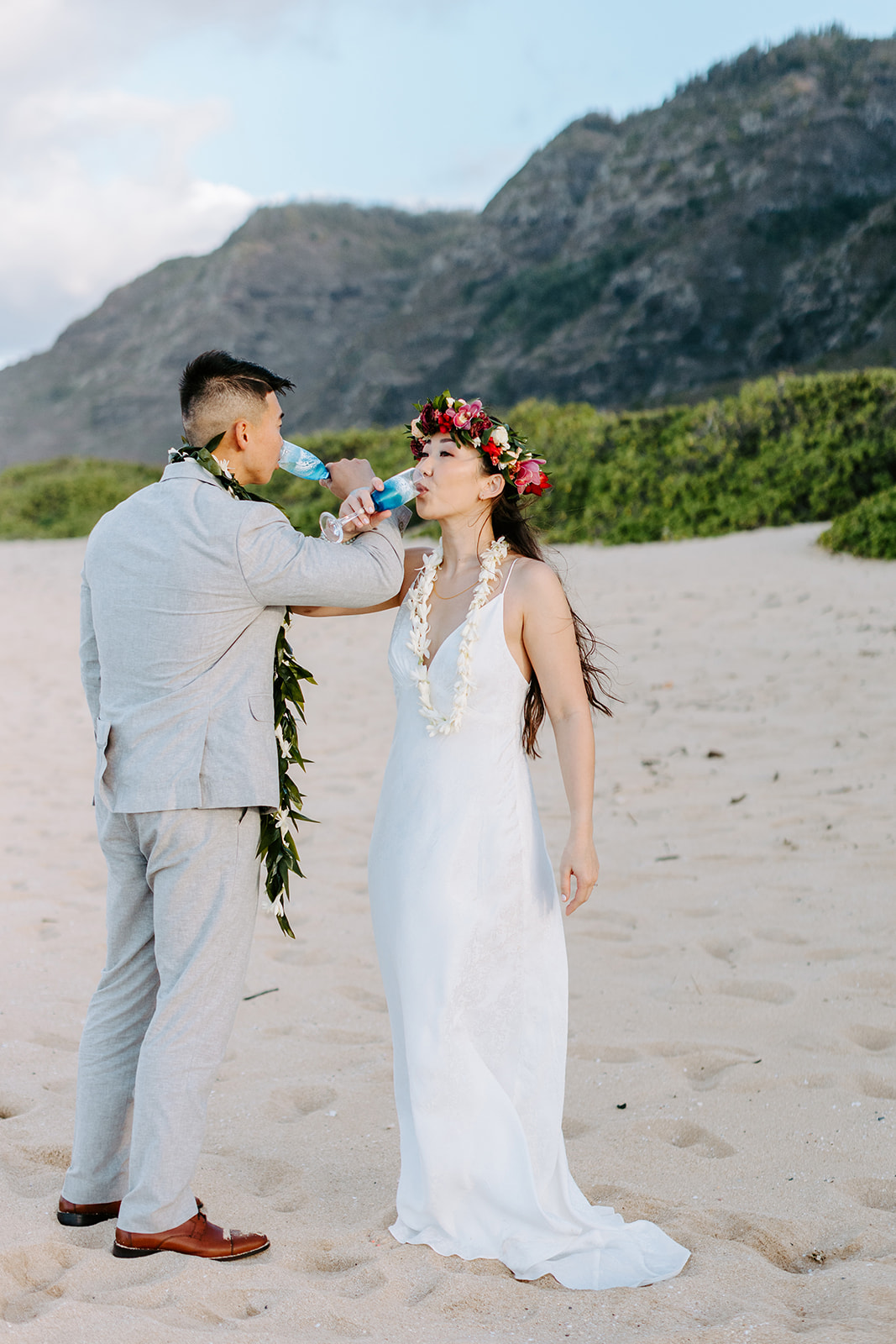 A couple who eloped on the North Shore of Oahu drink champagne. 
