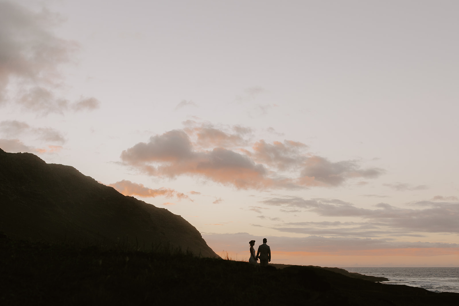A couple who eloped on the North Shore of Oahu watch sunset. 