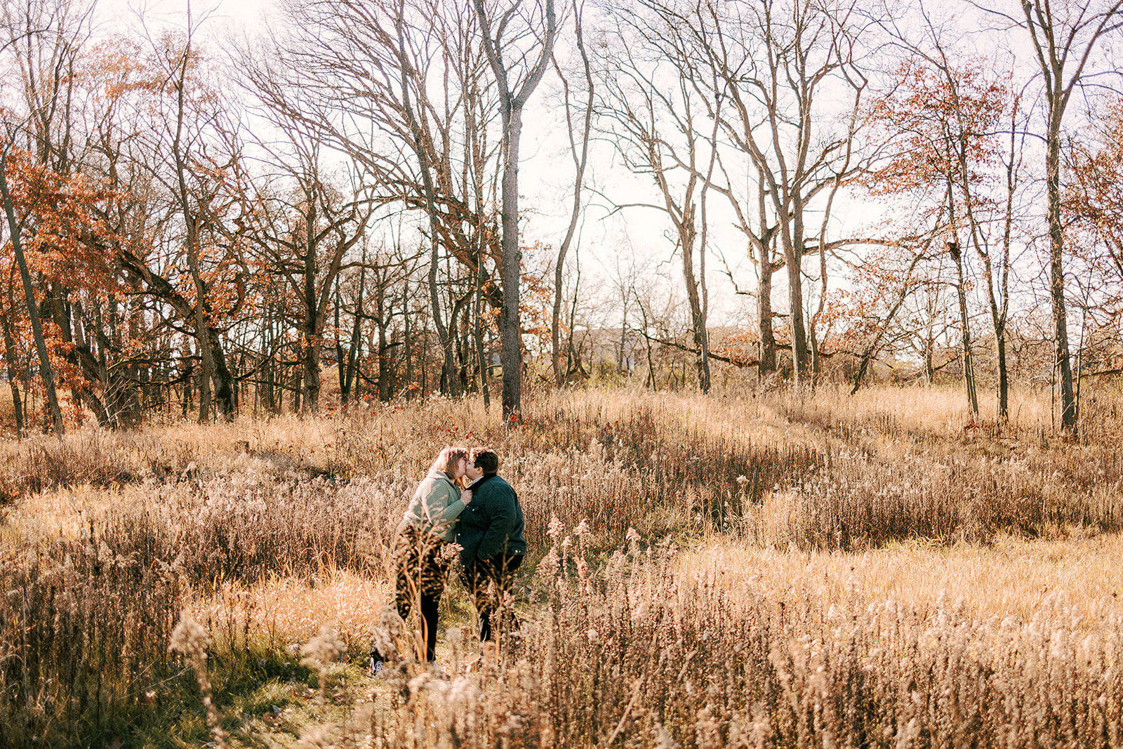couple kisses on the ice age trail during their engagement photos in madison wisconsin