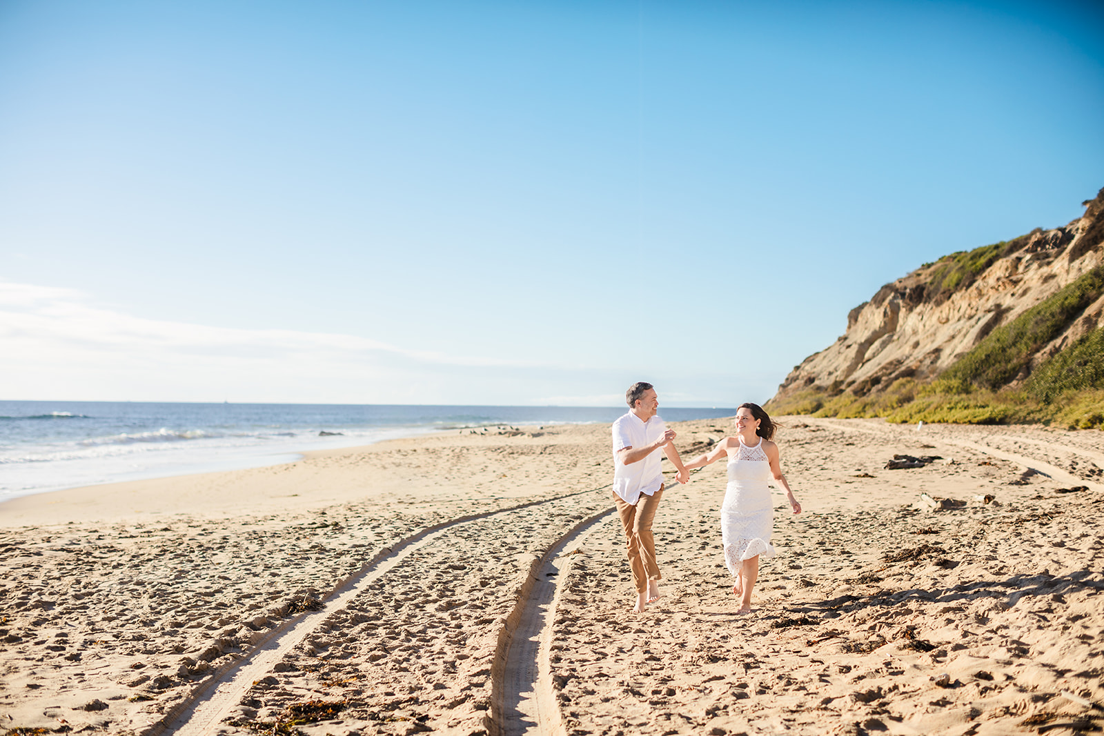 engaged couple running on the beach in Crystal Cove, CA