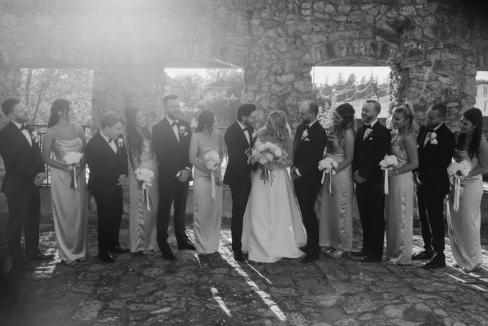 bridal party dressed in fall-inspired attire, standing in front of the historic Cambridge Mill