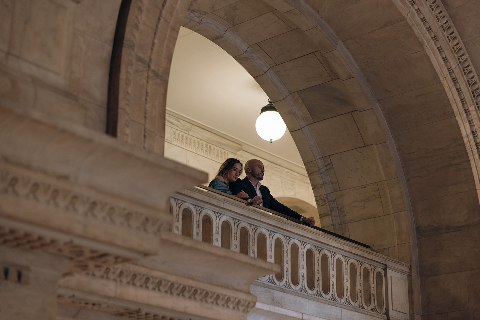 A couple cuddles inside the New York Public Library during their engagement session