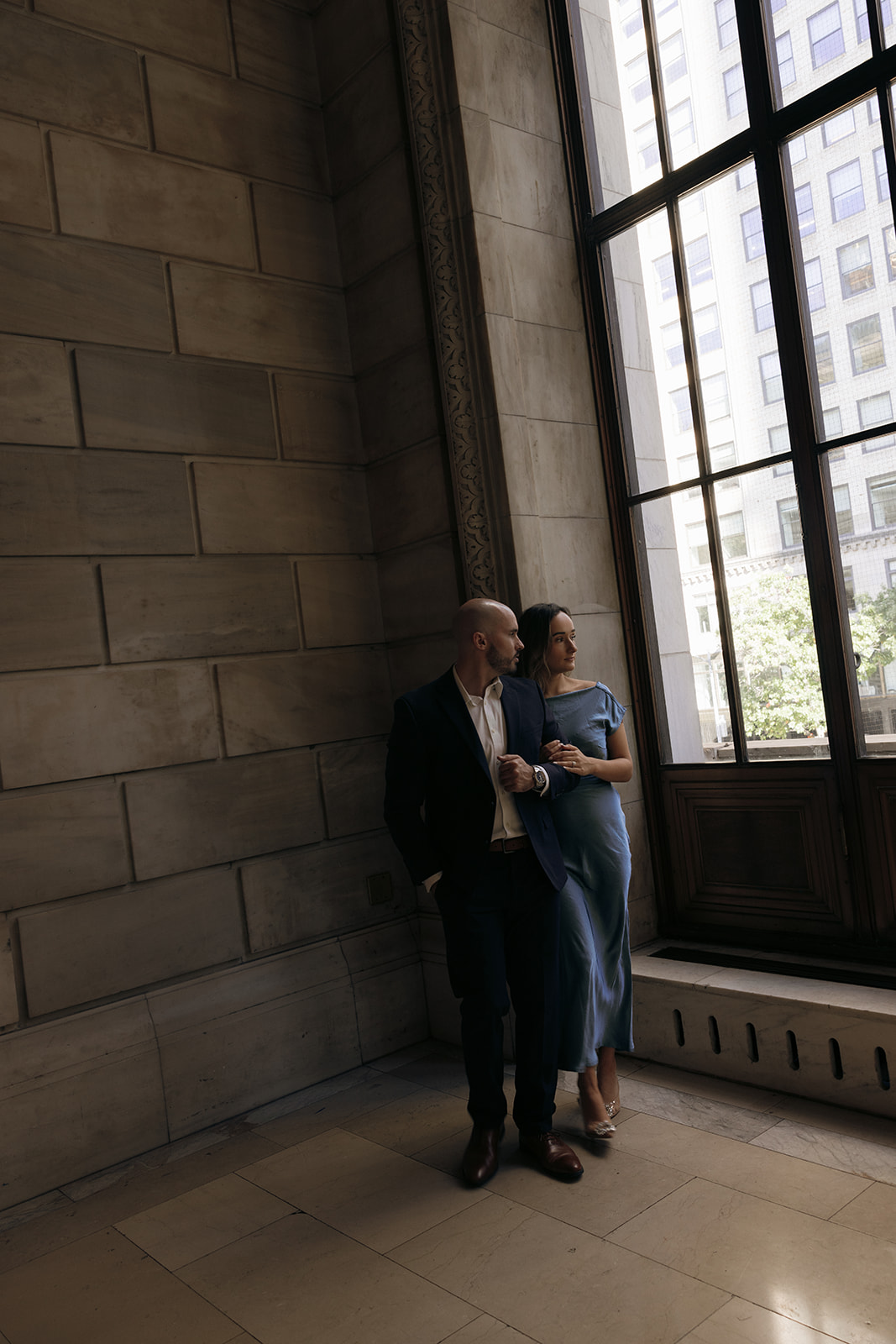 A couple cuddles inside the New York Public Library during their engagement session