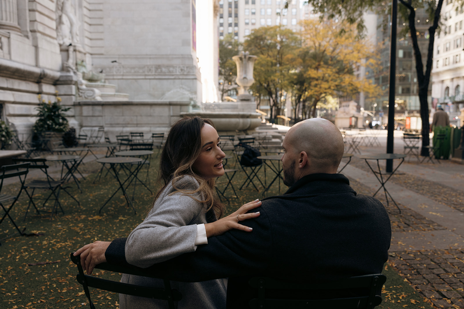 A couple sits together outside of the New York Public Library park