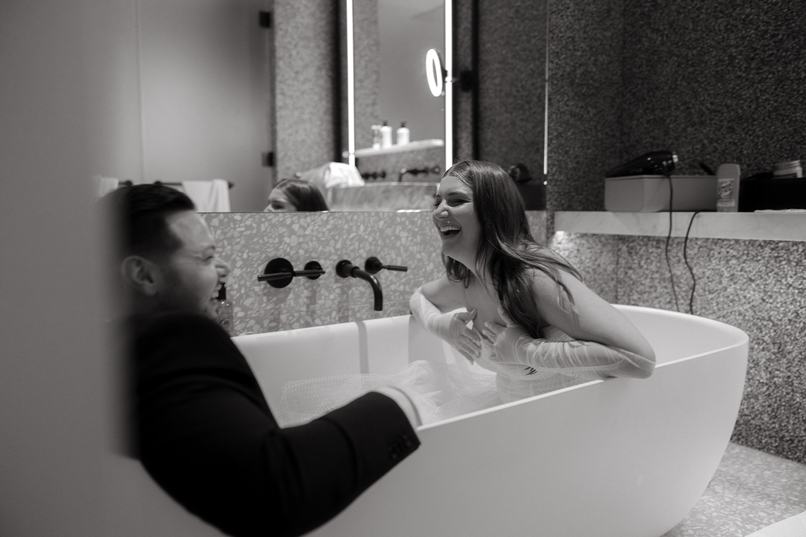A couple who eloped in NYC sit in their hotel bathtub and laugh together