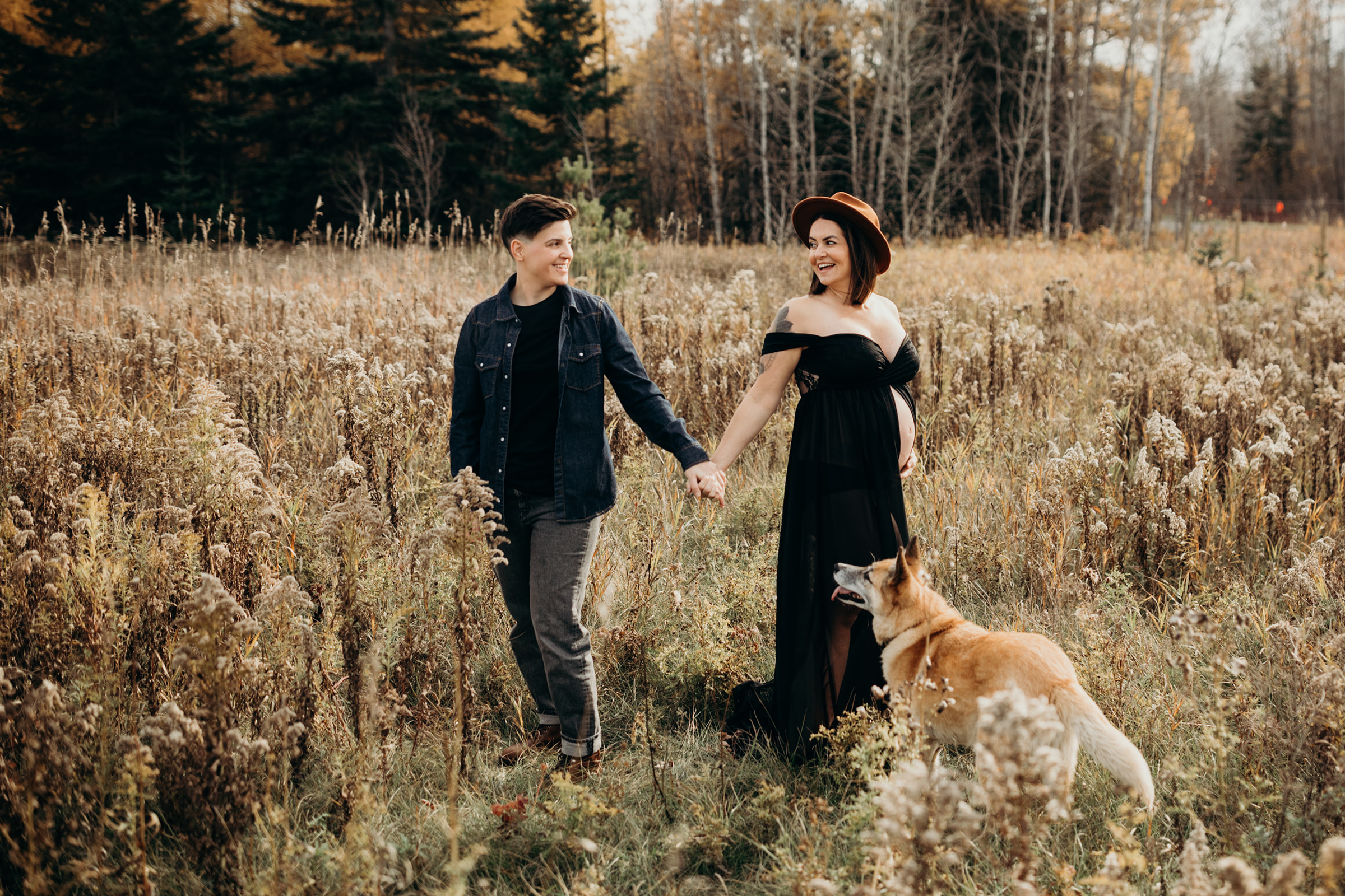 Couple holds hand in a field during their maternit photoshoot
