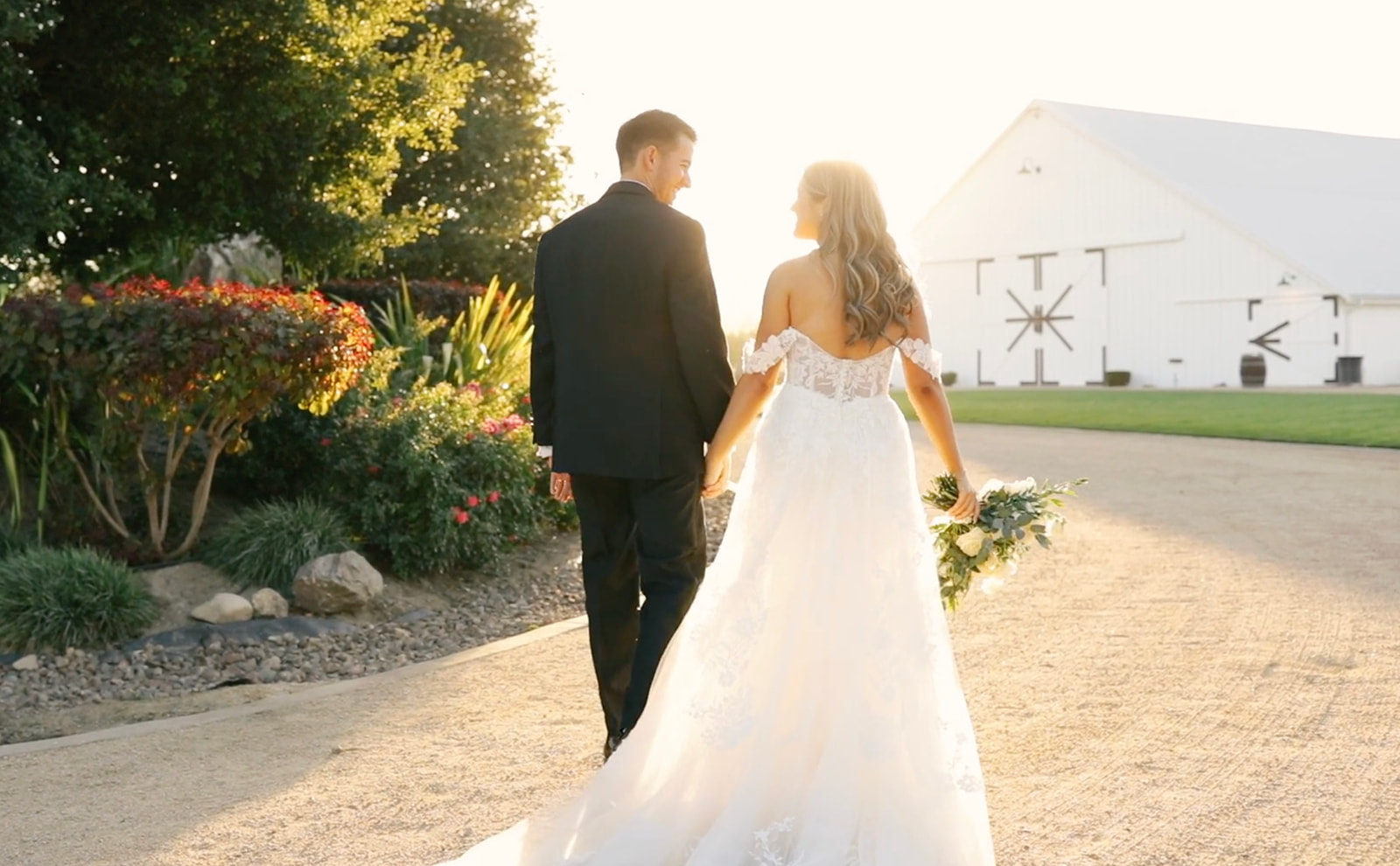 Bride and groom, hand in hand, walk into the golden sunset at the White Barn in San Luis Obispo