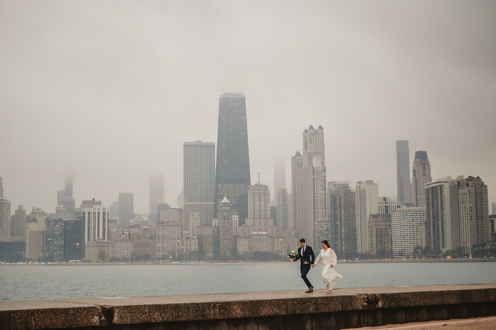 Intimate rainy day Chicago elopement wedding photography - Skyline over lake Michigan, couple walking on the beach