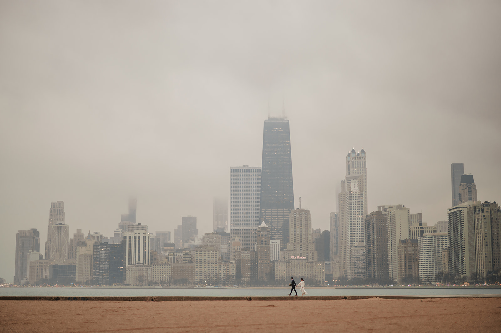 Intimate rainy day Chicago elopement wedding photography - Skyline over lake Michigan, couple walking on the beach