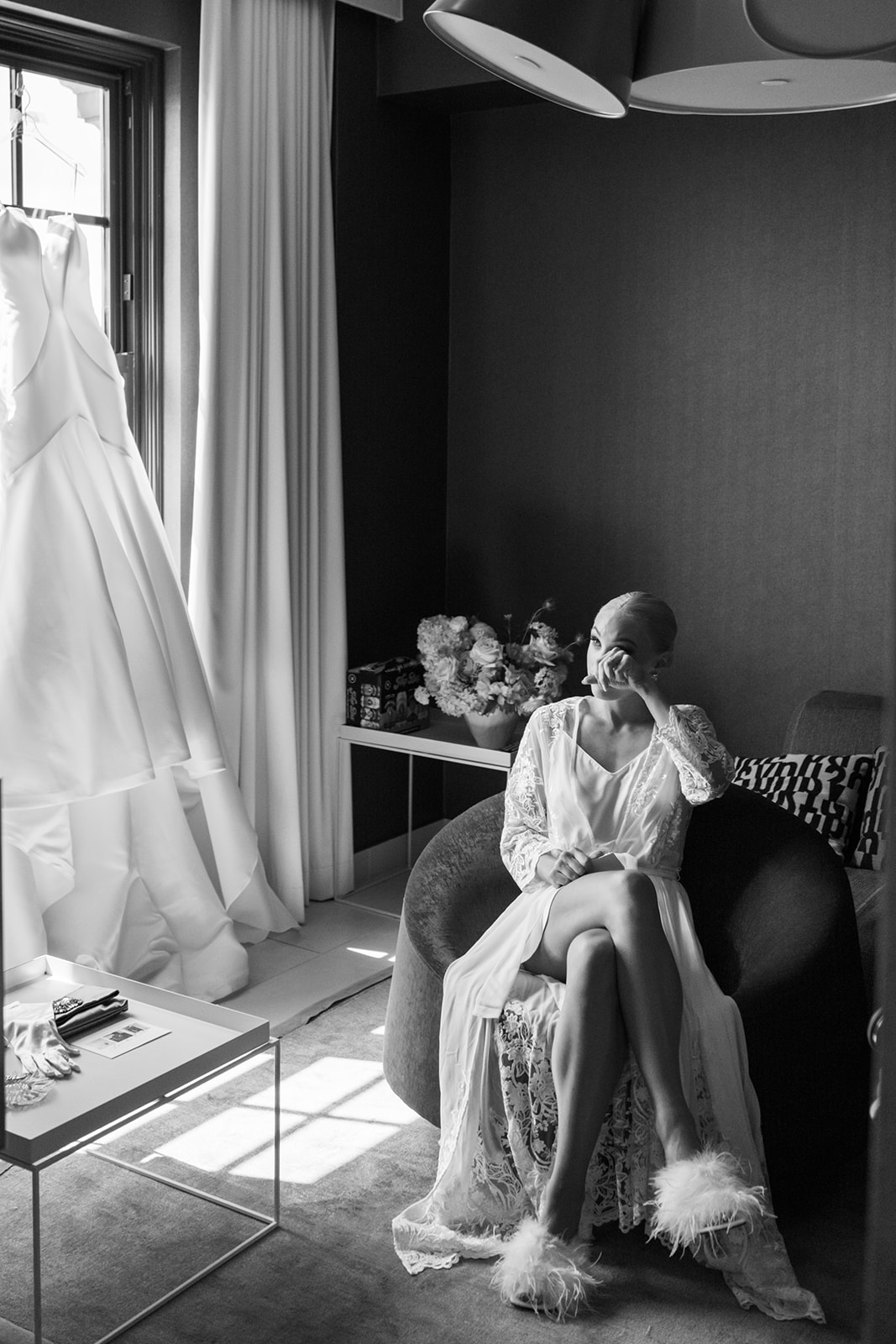 Bride reads a letter with her dress hanging in the window.