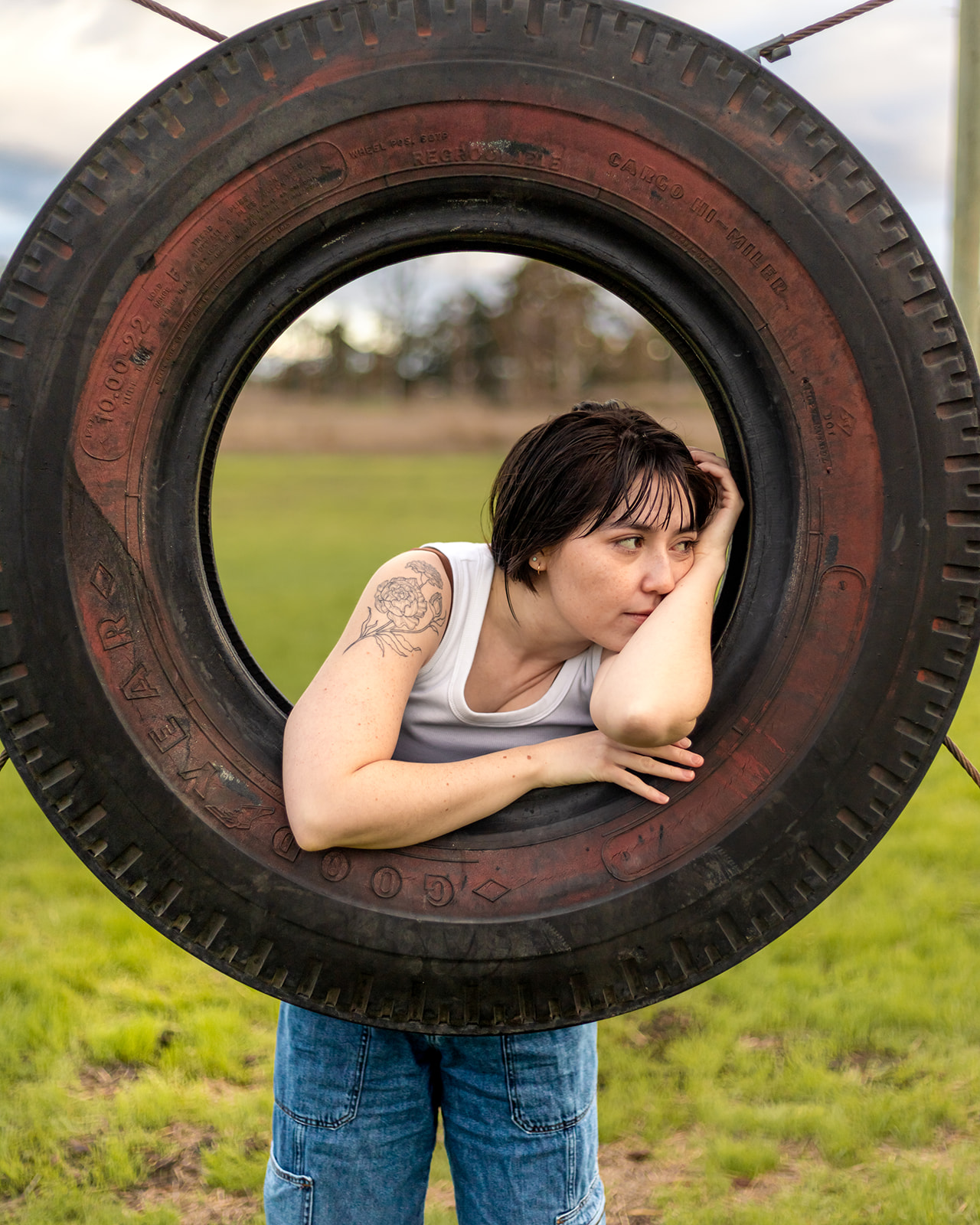 genderfull person leans on tire