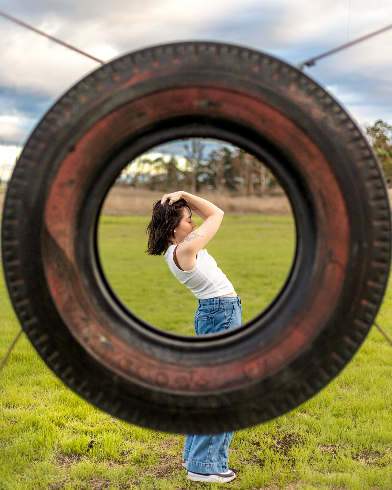 nonbinary person framed by old tire