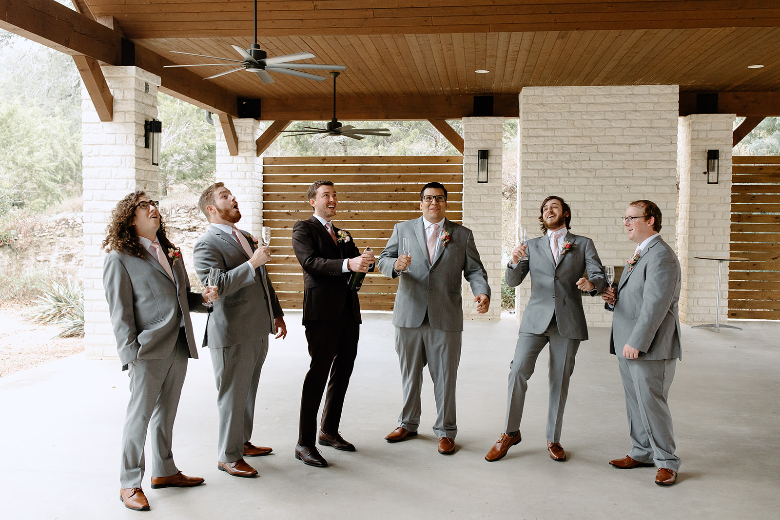 Groom and groomsmen popping champagne