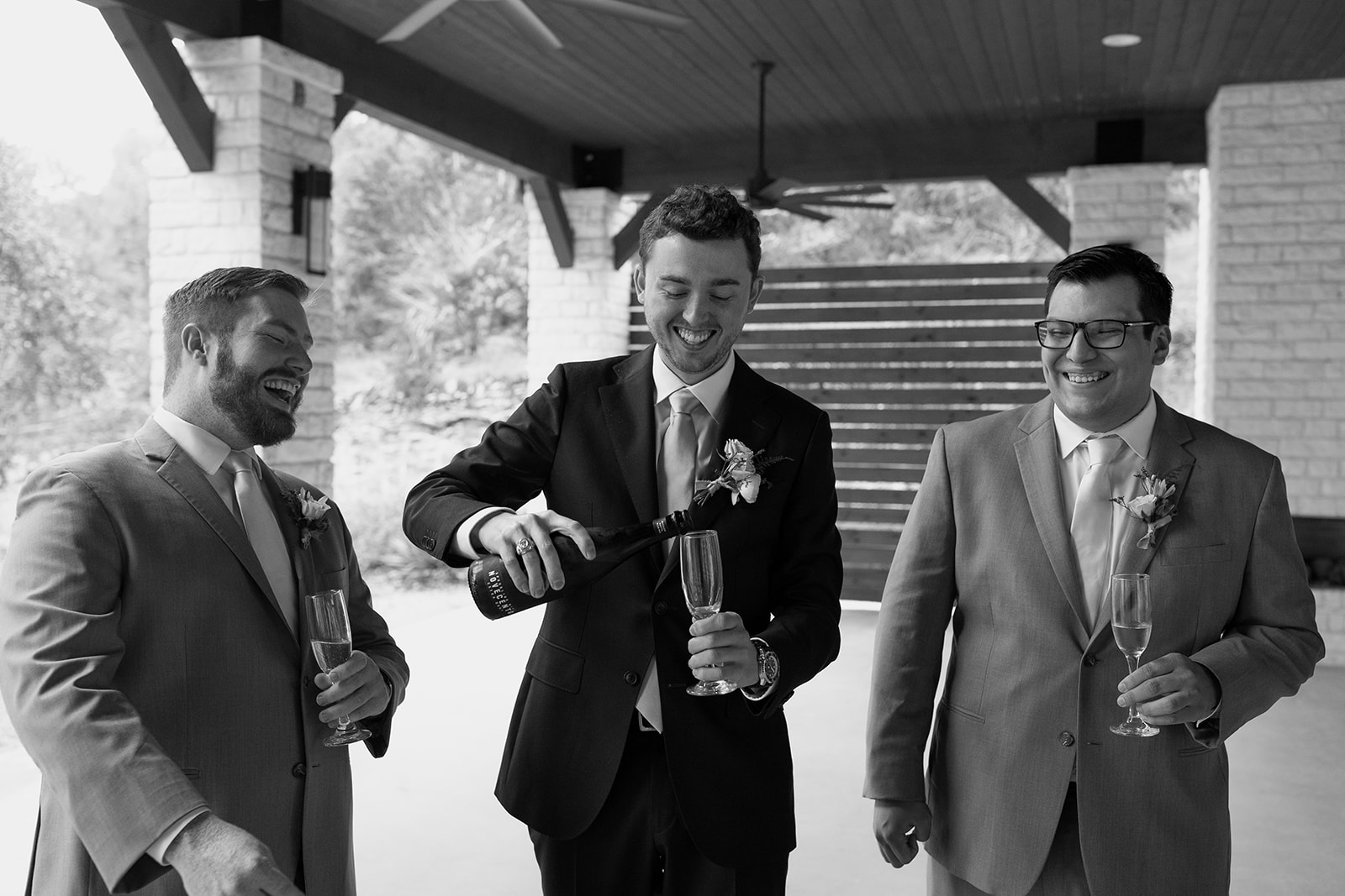 Groom and groomsmen popping champagne