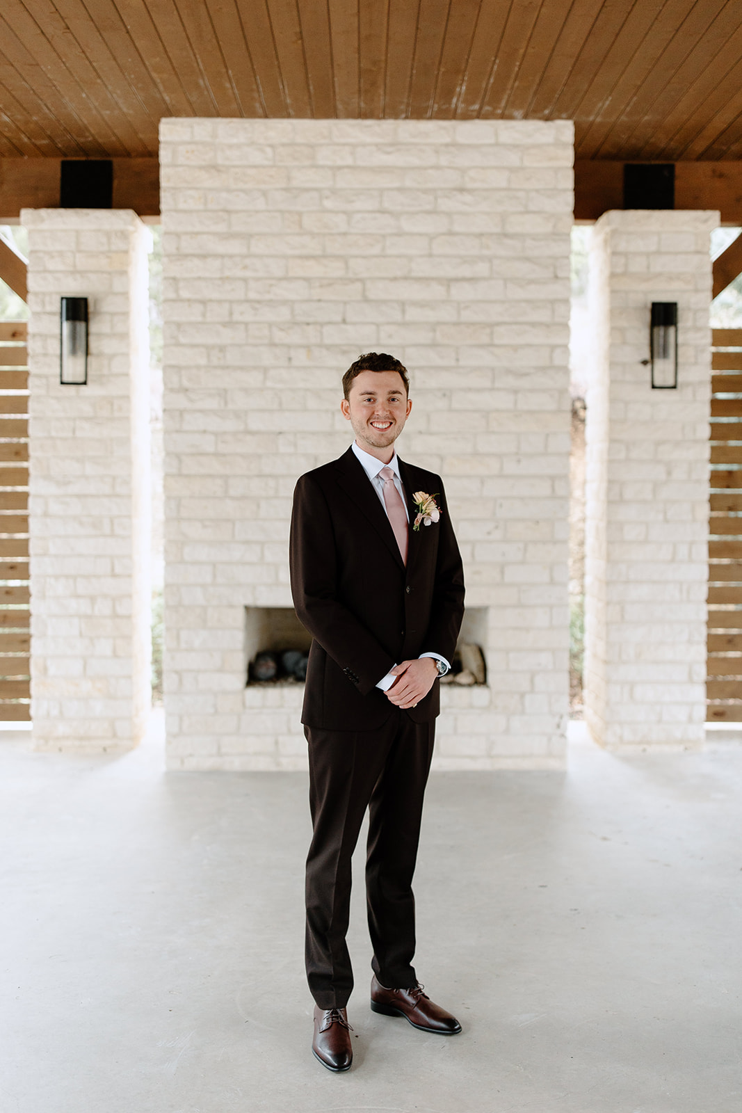Groom smiling in front of fireplace