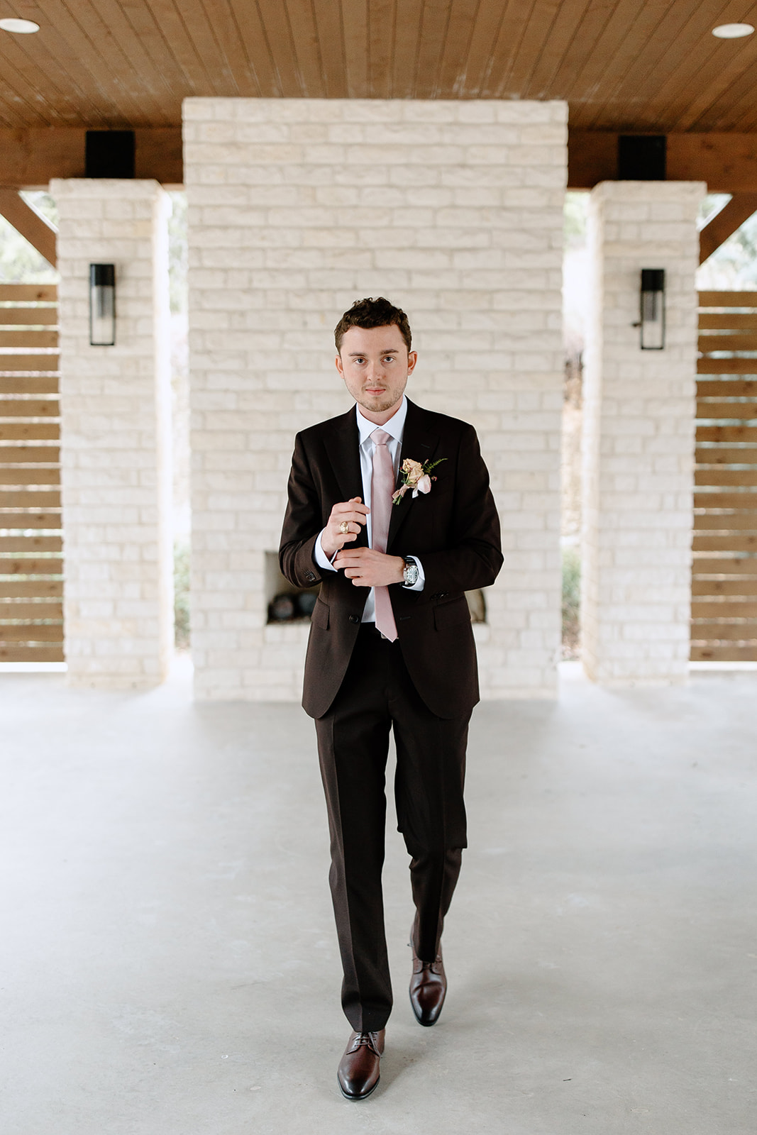 Groom smiling in front of fireplace