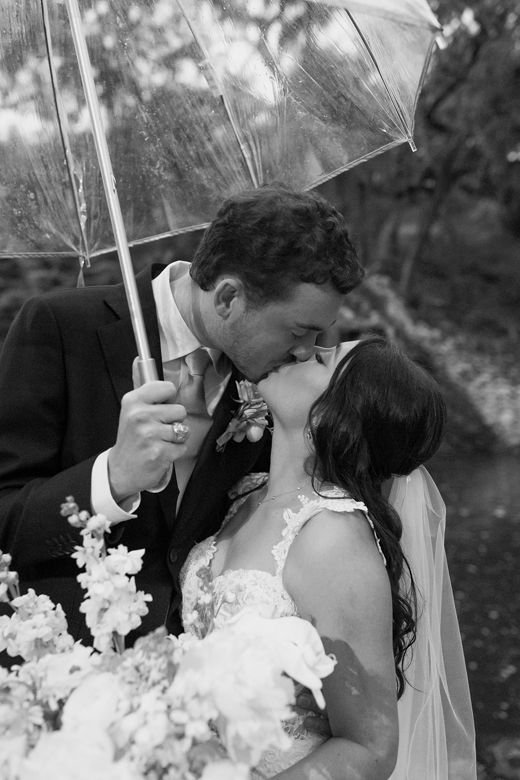 Bride and groom in front of a waterfall with an umbrella
