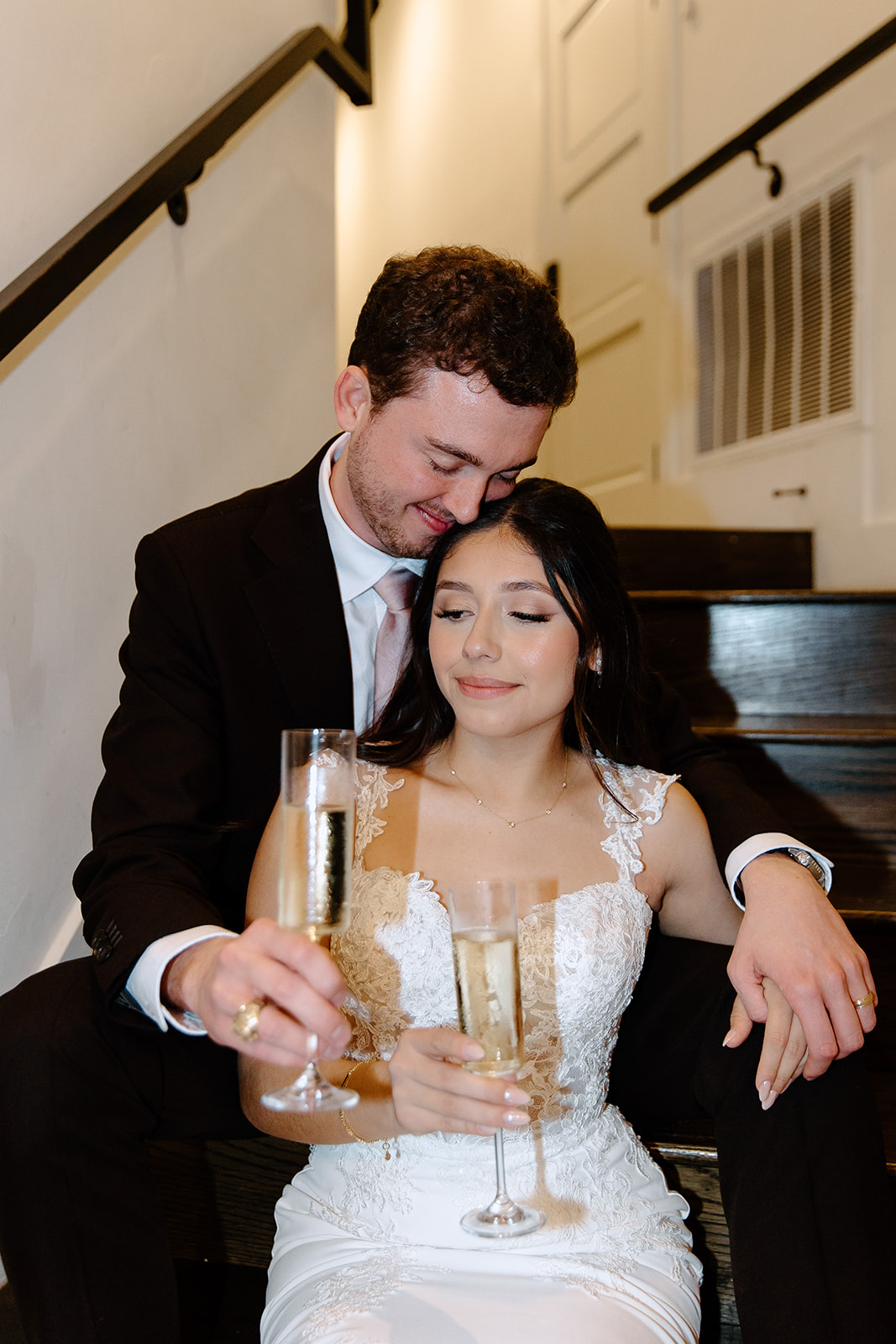 Bride and groom sitting on steps with champagne