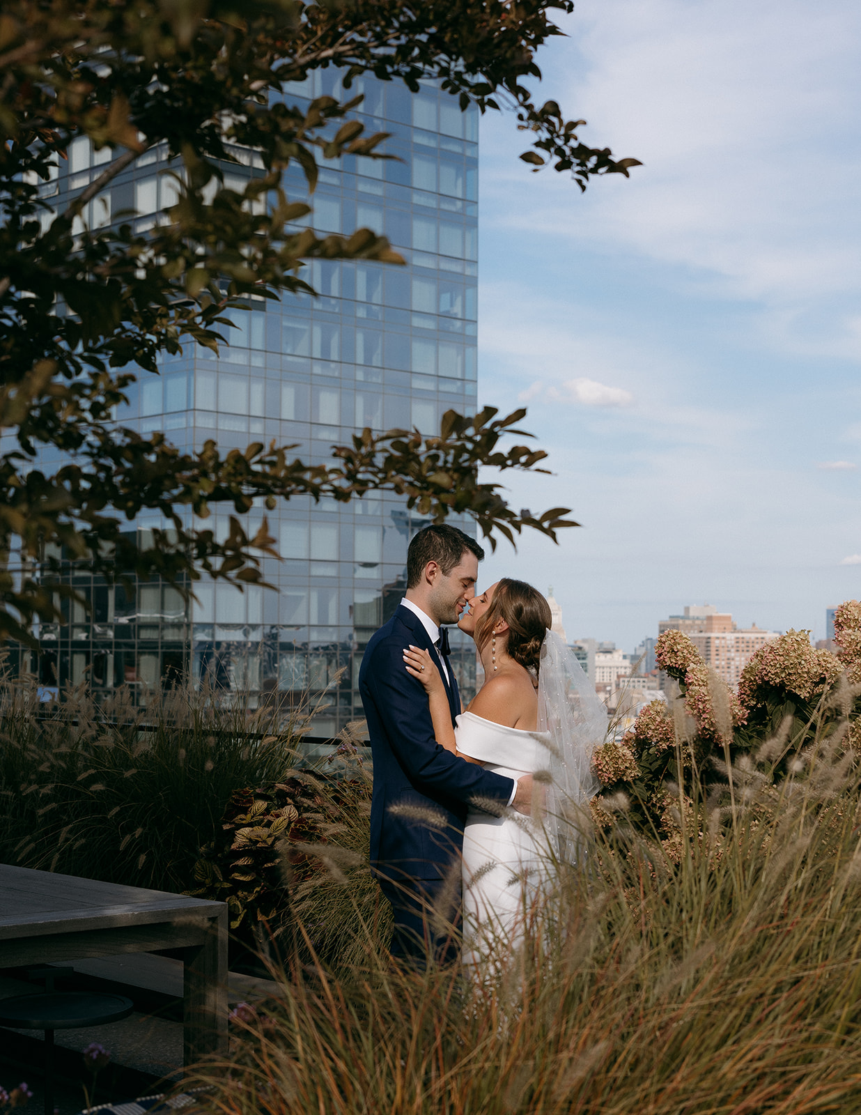 A bride and groom share a kiss on their wedding day on a rooftop in NYC